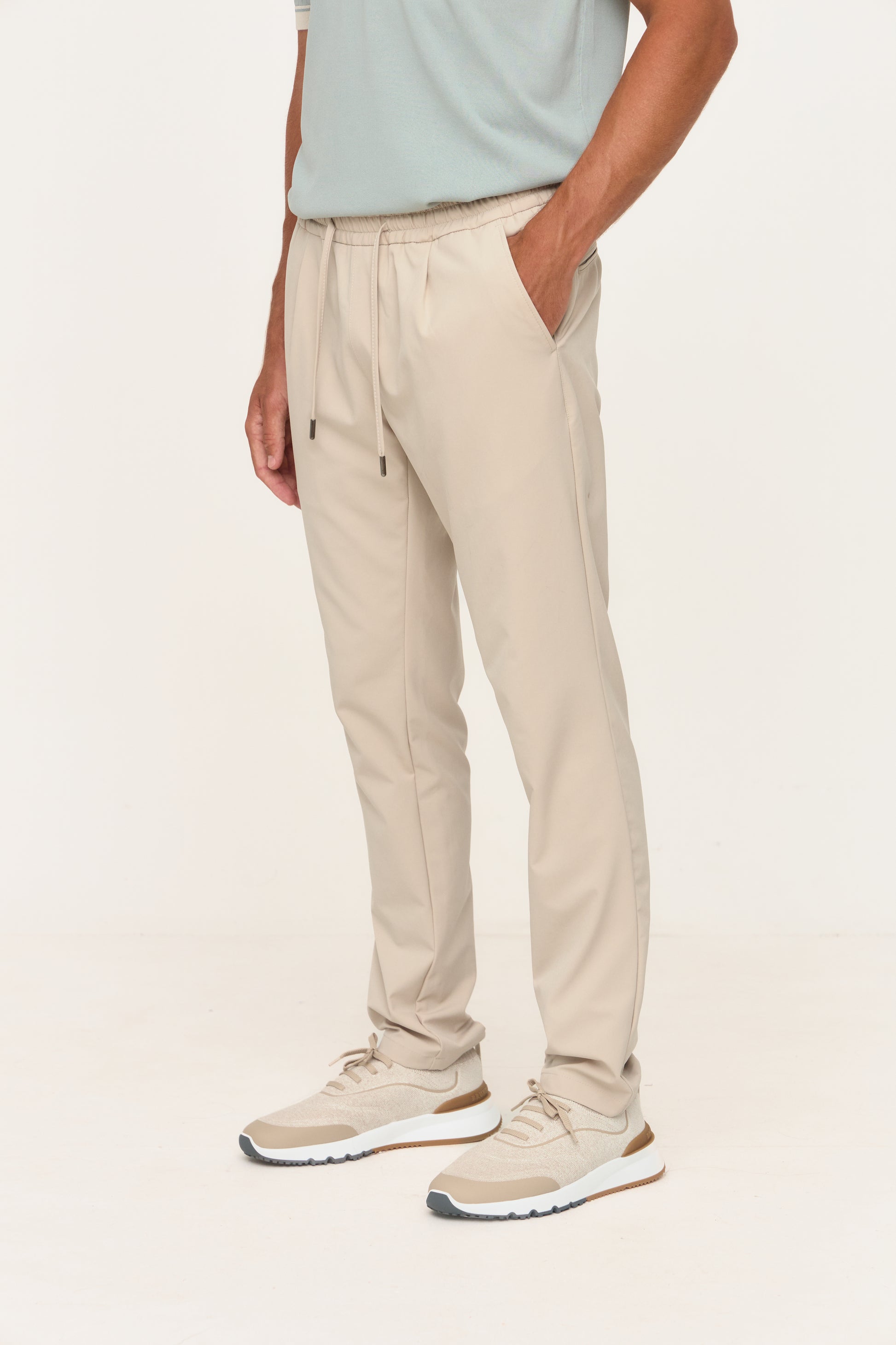 Person wearing beige pants and a light blue shirt on a white background